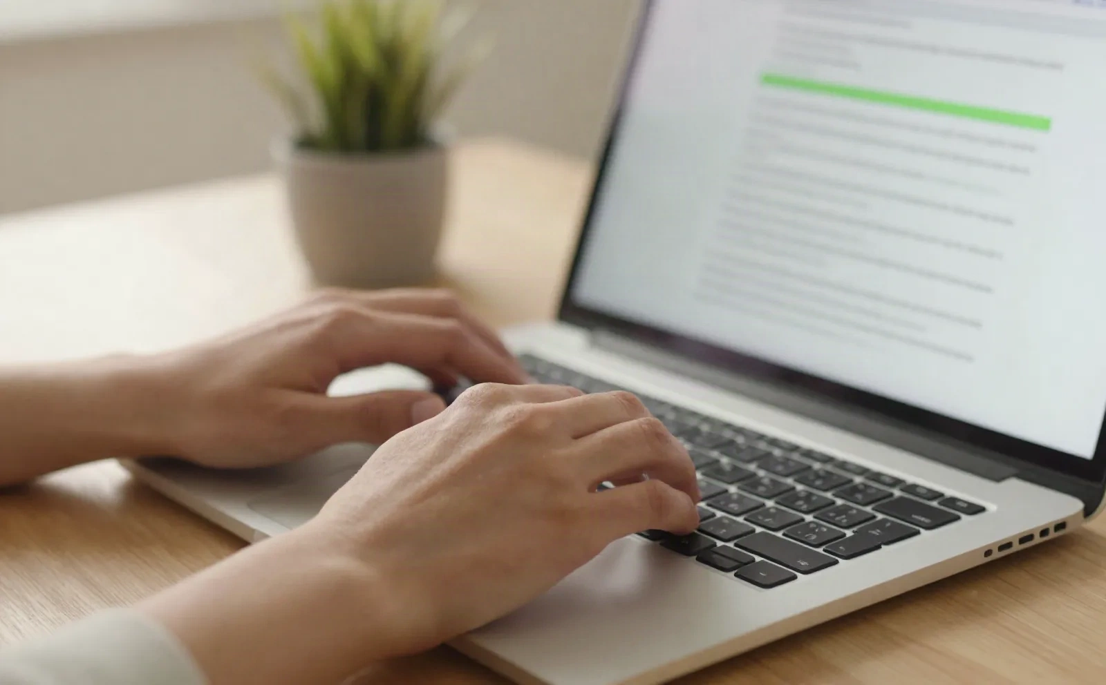 Close-up of hands typing on a laptop with an edited paragraph highlighted on screen