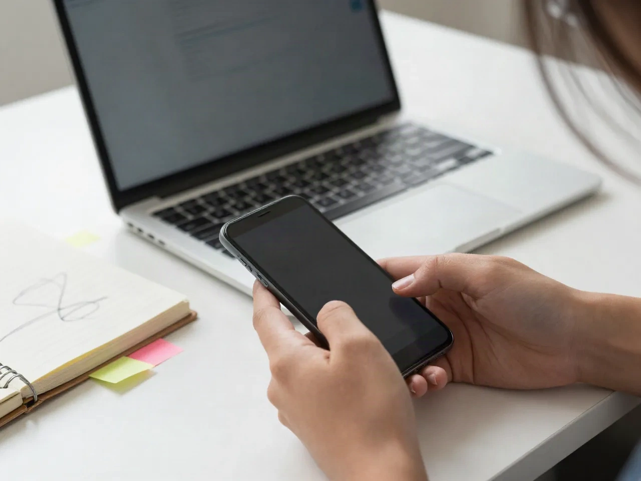 Person schreibt am Smartphone neben Laptop und Notizbuch eine Antwort