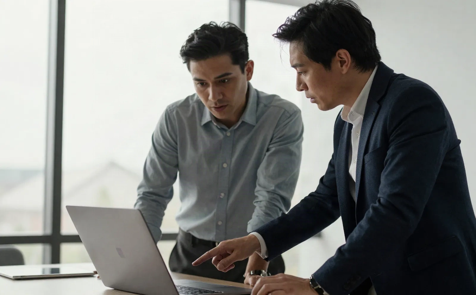 Two colleagues reviewing a highlighted contract on a laptop screen in an office