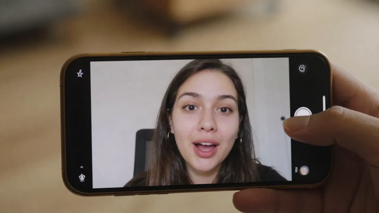 Creator filming an authentic talking-head video on smartphone for social media - what does UGC mean